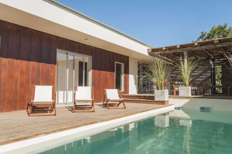 Información de CASAS PE147 de inmobiliaria ESTEVARENA en el barrio JOSE IGNACIO 
 Casa terminada hace un año, veraniega, que se desarrolla en una planta, dividida en dos sectores por la piscina que está rodeada de un deck con reposeras. Por un lado está el living comedor integrado, luminoso con cocina independiente y despensa. Y en el sector enfrente están los 4 dormitorios, en los exteremos encontramos las dos suites y en el medio están los dos dormitoris que comparten un baño completo que también hace las veces de baño social, al estar cerca de la pileta. Bien equipada con aire acondicionado en todos los ambientes, direct tv en el living, ropa blanca (un juego por cama). Parrillero con comedor exterior y lindo estar exterior para disfrutar el afuera. 